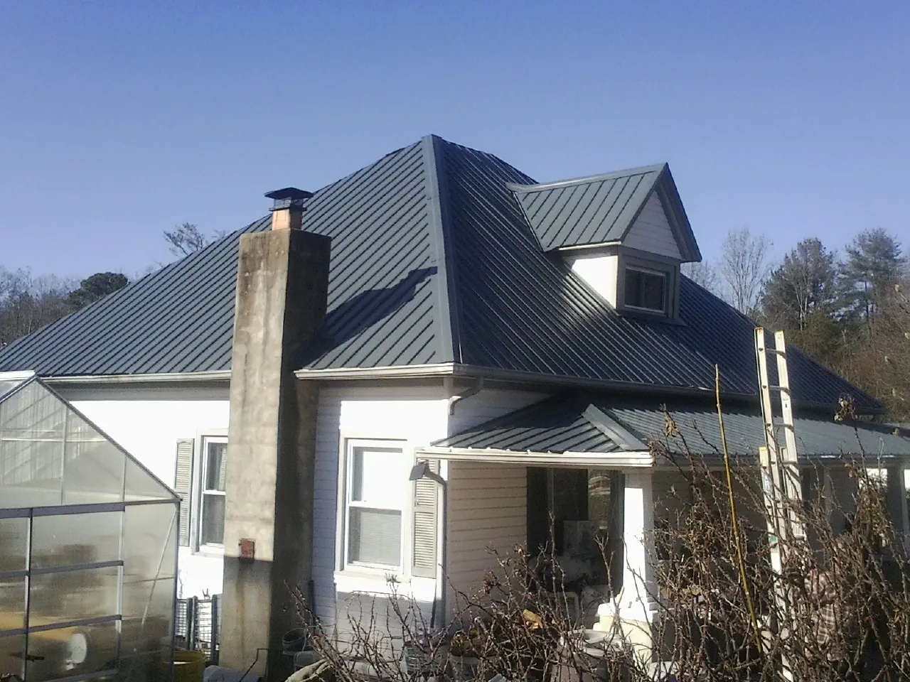 Dark blue standing seam metal roof on a white farmhouse with dormer — Slate & Tile Roof Repair by Roofing Brothers in Oakman