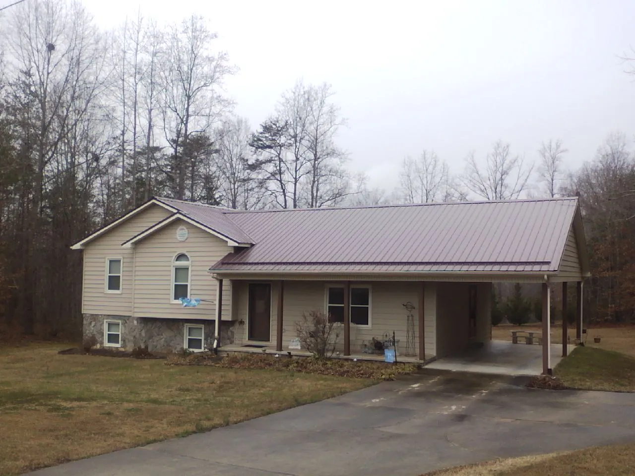 Burgundy metal roof on a tan split level home with an attached carport in Oakman