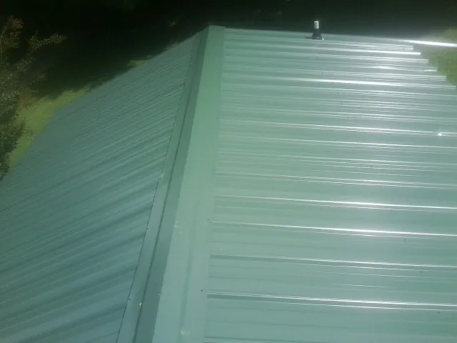 New green metal panels meeting at the ridge of a roof — Flat Roof Repair work by our crew in Oakman