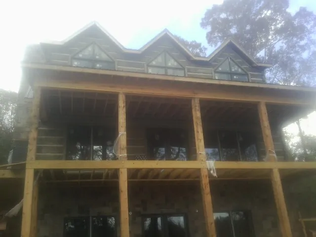 Dormers and porch framing on a large log home under construction — Roof Coating work by our crew in Oakman