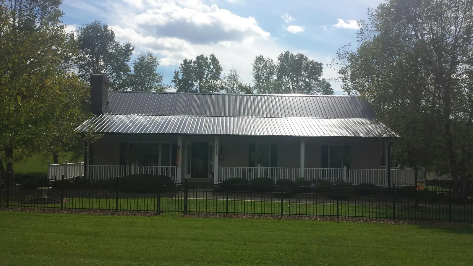 Gray metal roof on a brick ranch with a full width front porch — Gutter Guard Installation work by our crew in Oakman