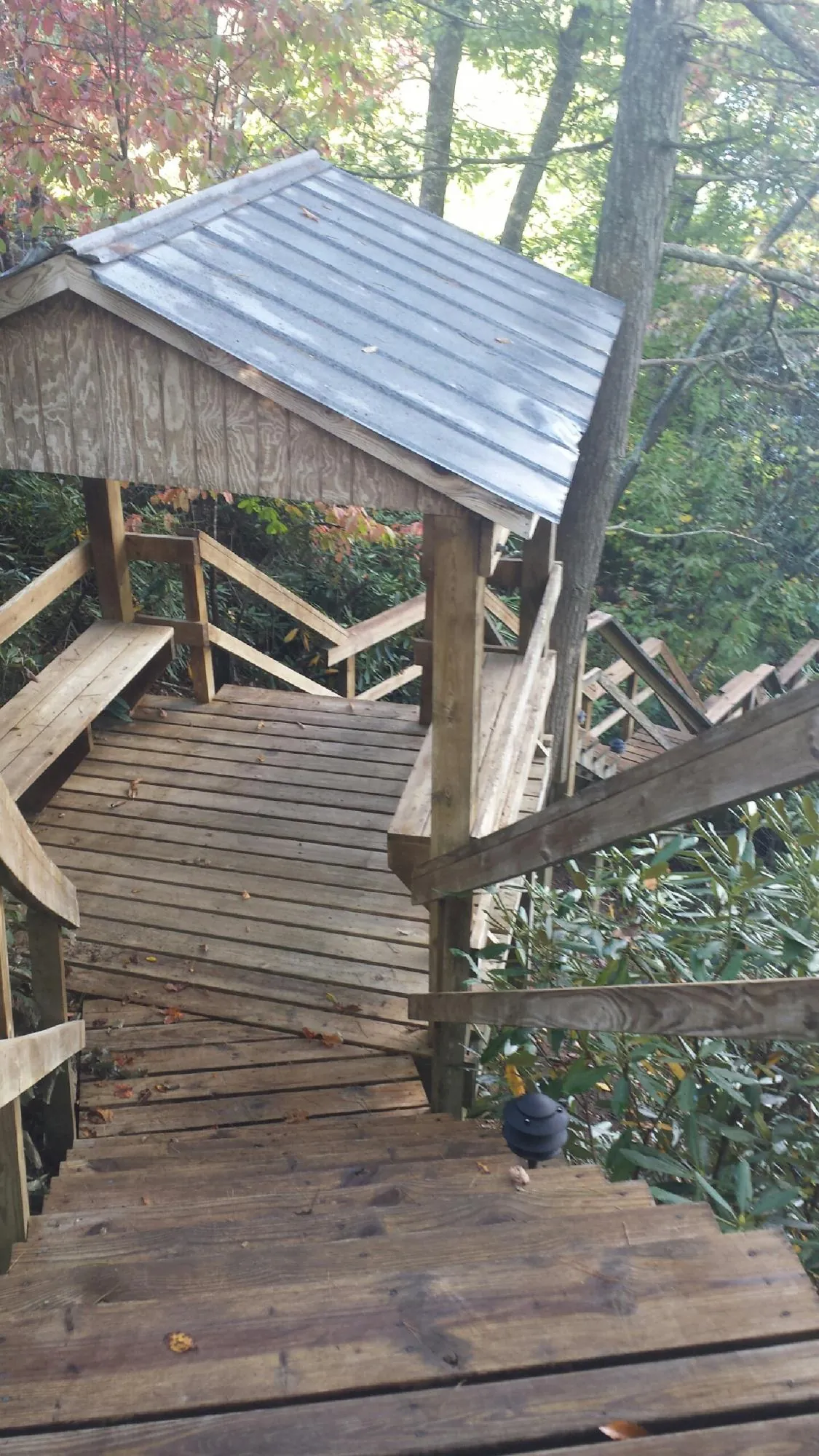 Metal roofed shelter over wooden steps on a wooded walkway — Skylight Repair & Installation work by our crew in Oakman